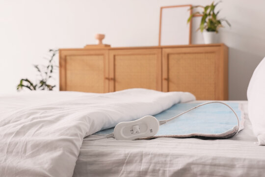 Electric heating pad on bed in light room, closeup