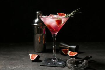 Obraz premium Glass of tasty fig lemonade and bartender tools on black grunge background, closeup