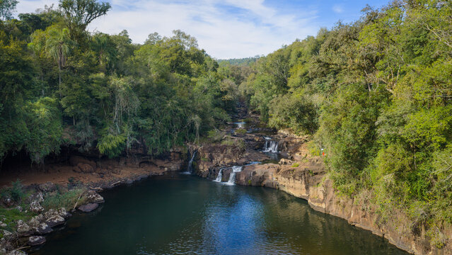 Scenic waterfall and natural pool surrounded by native forest at Gruta India park.