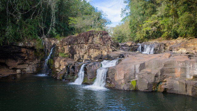 Multi-tier waterfall flows through rocky terrain inside Gruta India nature park.