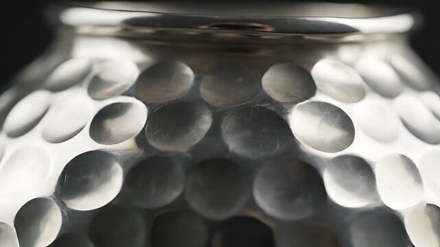 Closeup of a Hammered Metal Vase with Reflective Surface.
