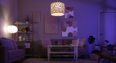Interior of stylish living room with cozy sofas, coffee table and glowing lamps at night © Pixel-Shot