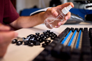 Fototapeta premium Closeup of enthusiast working on keyboard switch modifications. Detailed view of technician applying lubricant and adjusting blue switch components meticulously