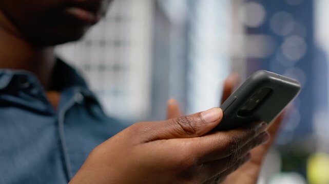 Close up of woman browsing web on mobile phone walking through city street downtown, surrounded by tall buildings. Girl checking directions and sightseeing suggestions, metropolis.