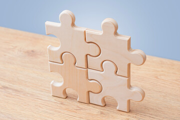 Wooden puzzle pieces connected on blue background with copy space. Teamwork, partnership and business integration concept for corporate strategy, collaboration, problem solving or workflow design. © vadish