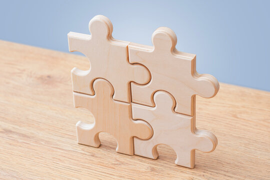 Wooden puzzle pieces connected on blue background with copy space. Teamwork, partnership and business integration concept for corporate strategy, collaboration, problem solving or workflow design.