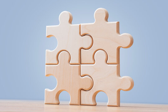 Wooden puzzle pieces connected on blue background with copy space. Teamwork, partnership and business integration concept for corporate strategy, collaboration, problem solving or workflow design.