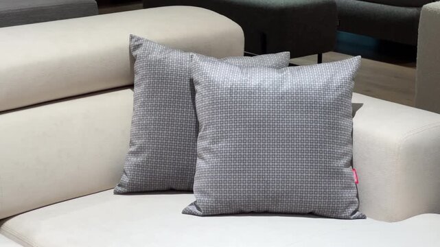 Parallax Shot: Two Gray Patterned Decorative Pillows on Modern White Leather Sofa | Luxury Hotel Lounge or Business Center Interior | Contemporary Furniture and Home Decor Detail