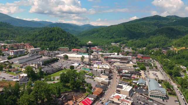 Aerial landscape of Gatlinburg city center with busy tourist streets, main Parkway filled with shops and restaurants, and scenic Smoky Mountains in the background.