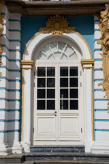 Fototapeta premium White double doors with glass panels are surrounded by intricate gold and blue decorations at Catherine Palace, showcasing exquisite architectural design