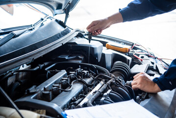 Fototapeta premium Close up Car Mechanic man hands repairing car auto repair shop. Close up hand man check engine oil level Locate dipstick, wipe clean, check dipstick level before fill up engine oil. open vehicle