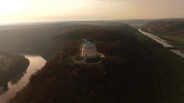Sunset aerial video of Befreiungshalle in Kelheim, Germany, landmark neoclassical monument on Michelsberg hill, overlooking Danube Gorge, Altmuehltal and Bavarian mountain valleys in autumn colors