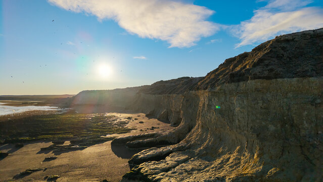Golden sunset illuminating dramatic coastal cliffs at Playa Las Canteras near Puerto Madryn Patagonia.