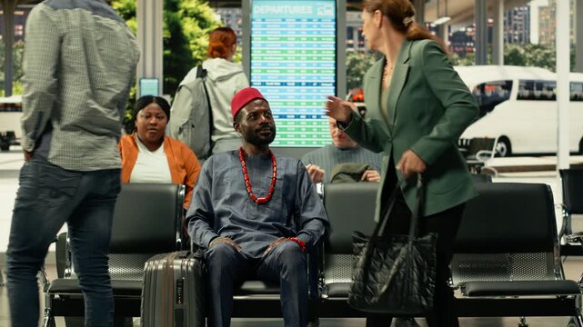Man in african traditional clothes sitting in bus station for long-haul journey, traveling by intercity coach with big luggage for relocation. Passenger waiting for highway bus departure.