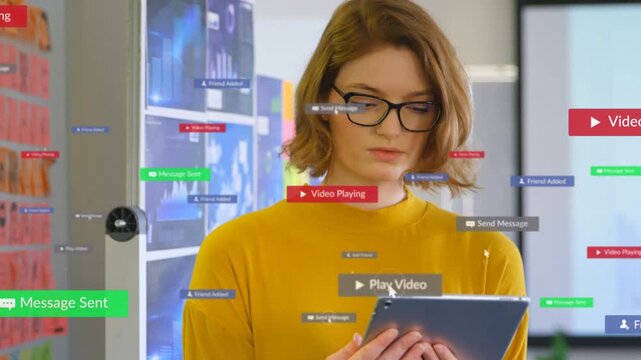 Woman holding tablet in tech office, looking down and causing UI badges to appear, managing media