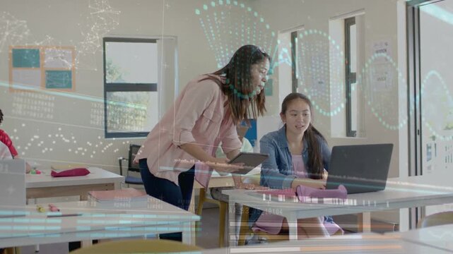 Teacher leaning over student laptop, holding tablet and guiding coding task with DNA helix overlay