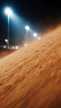 close-up of dusty earth bank at night, strong winds blowing particles, bright stadium lights in background, dramatic atmosphere