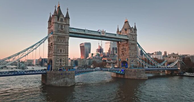 Tower Bridge, a historic bascule and suspension bridge, connecting boroughs over the River Thames with the city skyline illuminated by the setting sun. Aerial view drone shot of modern London city