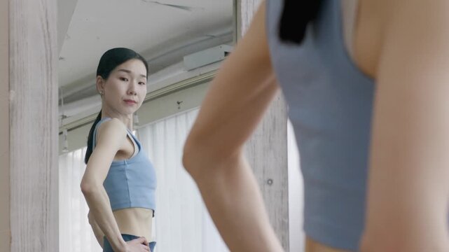Asian Woman in Yoga Wear Checking Body Shape in Mirror