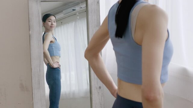 Asian Woman in Yoga Wear Checking Body Shape in Mirror