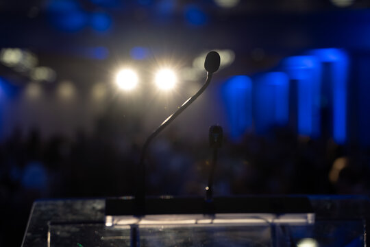 Close up of microphones on conference stage with blue lights.
