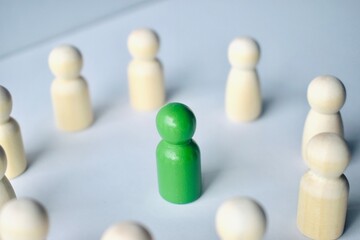 Obraz premium A green wooden peg placed in the center of a circular arrangement of natural wood pegs.