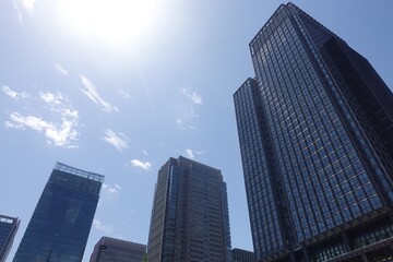 Obraz premium Looking up at Marunouchi office buildings with backlit blue sky