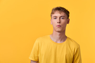 Fototapeta premium Minimalist image of a young man in a bright yellow shirt against a solid yellow backdrop, emphasizing color harmony, casual style, and contemporary fashion visual.