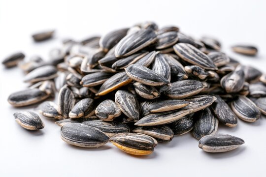 A close-up image of a pile of striped sunflower seeds on a white surface.