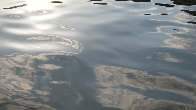 Silent sky and sunlight reflections on rippling water surface, abstract nature background footage