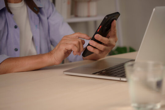 Senior man hands touching smartphone screen using mobile banking app at desk