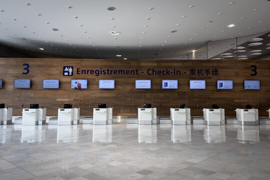 PARIS, FRANCE - MARCH 6, 2026: Check in desks at Paris Charles de Gaulle Airport terminal 3, with empty counters, overhead signage, passenger service screens and a modern terminal interior.