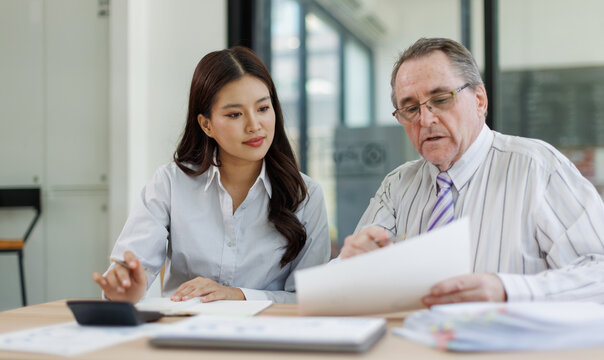 Experienced senior male manager providing professional mentorship and business guidance to a young asian female employee. Fostering career development and teamwork