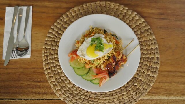 Traditional Indonesian mie goreng served with fried egg, vegetables, and savory spices.