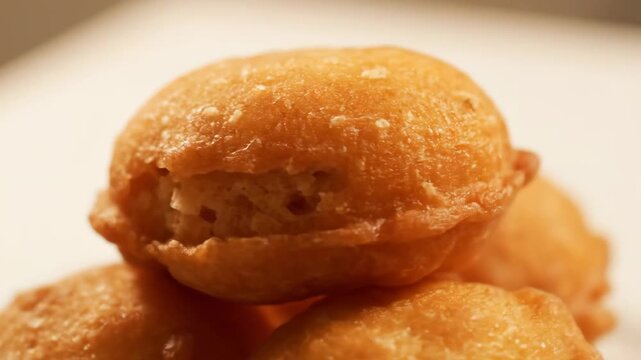 Extreme close-up of golden brown deep-fried sweet dough balls (fritters or doughnuts) stacked, emphasizing crispy texture
