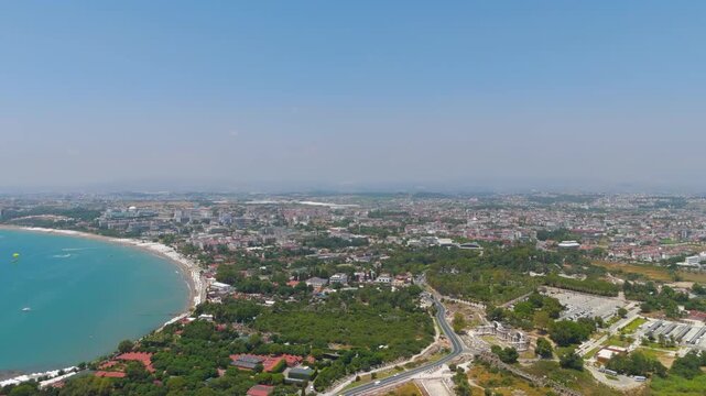 Side, Manavgat, Turkey. Panoramic drone flight over the ancient peninsula, archaeological ruins merging with modern resort town along turquoise Mediterranean coastline, clear summer day. Aerial View,