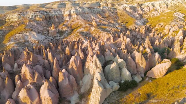Goreme, Nevsehir, Turkey. Devrent Valley fairy chimneys, whimsical volcanic tuff formations glowing in golden sunset light, aerial view over the eroded Anatolian plateau. Aerial View, Departure of th