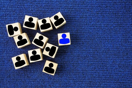 Wooden cubes with different people and one person icons. Concept for company and human resorce manangement. new employees or students. new team member to a group. Business management concept 
