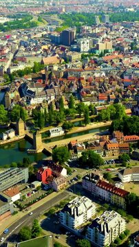 Vertical video. Strasbourg, France. The Vauban Dam spanning the River Ill with its stone arches, Drone footage over Petite France and the cathedral spire under clear summer skies.. Drone footage. Ric