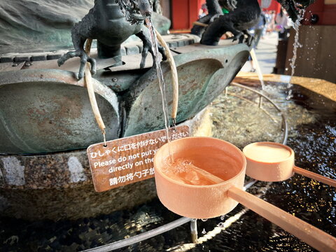 Japanese purification fountain with dragon sculpture and wooden ladles at Sensoji Temple, Tokyo, Japan.