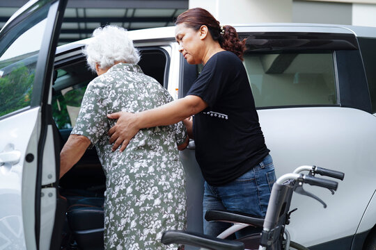 Caregiver help Asian elderly woman disability patient get in her car.