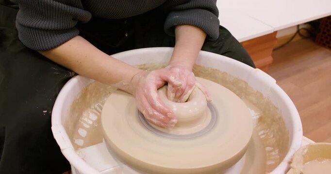 Hands craft clay. Pottery workplace. Unrecognizable experienced woman artisan shaping raw using wheel in professional ceramic studio.