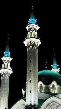 Vertical video. Kazan, Russia. Kul Sharif Mosque, illuminated white marble facade and turquoise domes rising against the night sky, low-angle view from the Kremlin grounds. Rich colors