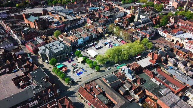 Aerial drone footage of a St George&rsquo;s Day event taking place in Salisbury Market Square, showing stalls, crowds, historic buildings, streets, rooftops, and the city centre from above.