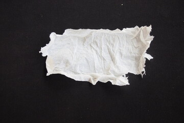 ​Torn and crumpled piece of white tissue paper isolated on a black background. Ripped soft napkin scrap with rough tattered edges and copy space for text. © Roemah feyza images 