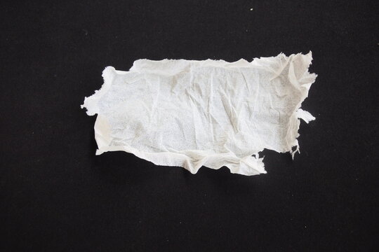 ​Torn and crumpled piece of white tissue paper isolated on a black background. Ripped soft napkin scrap with rough tattered edges and copy space for text.
