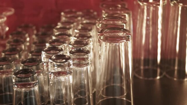 Clean glass. Transparent barware. Dry empty cocktail crystal wineglass in row upside down on bar counter in restaurant.
