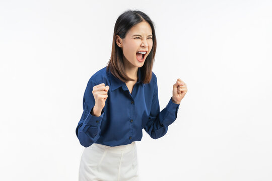 Excited young Asian businesswoman celebrating success with joyful expression in smart casual outfit isolated on white studio background.