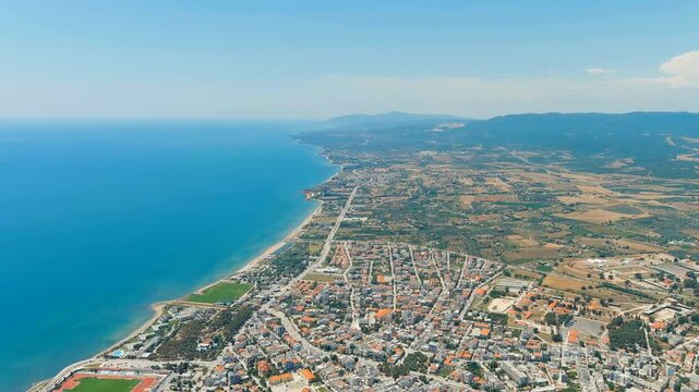 Alexandroupolis, Greece. Aerial panorama of the Thracian Sea coastline, dense terracotta rooftops and the historic 1880 lighthouse at the harbor entrance. Drone footage