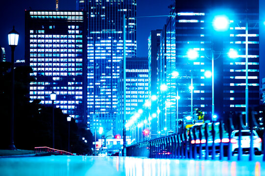 Futuristic corporate high-rises in Tokyo at night with cyber-blue lights and road reflections.